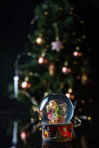 Scena di natale con albero, luci e globo di neve. messa a fuoco selettiva