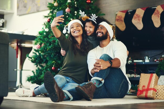 写真 クリスマスの自撮り家族と休日とお祝いの母と幸せな父と子供の笑顔で幸せな家族との写真でクリスマス ツリーの装飾の贈り物と幸せを保持しています。