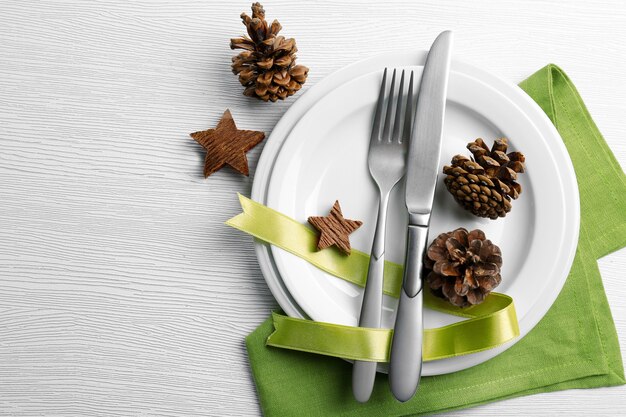 Christmas serving cutlery on plate and napkin over light wooden table