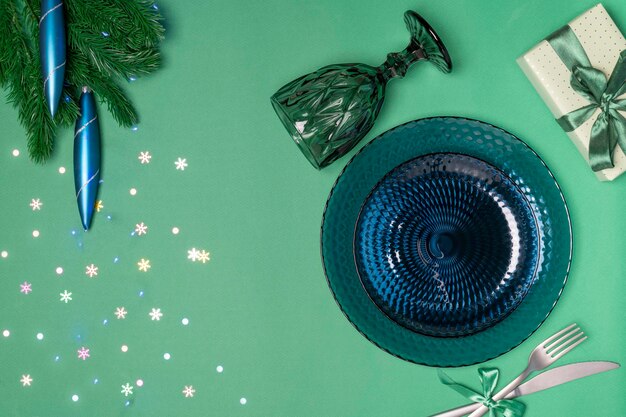 Рождественская сервировка Темно-синяя стеклянная посуда еловая ветка с елочными игрушками боке из гирлянды