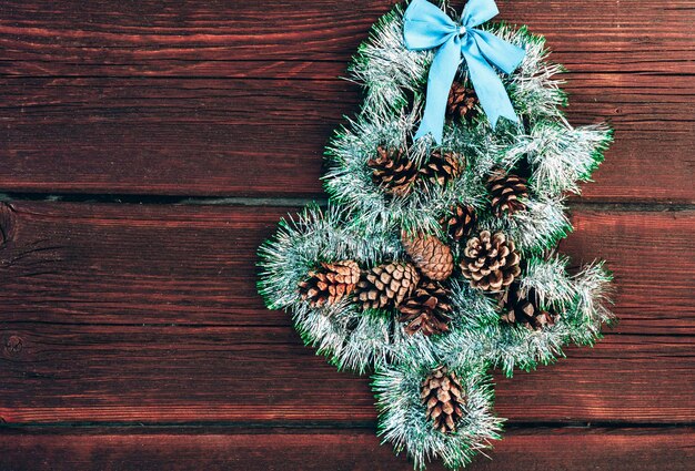 円錐形と青い弓を持つクリスマスツリーの形をしたクリスマスの光沢のある緑色の見掛け倒し