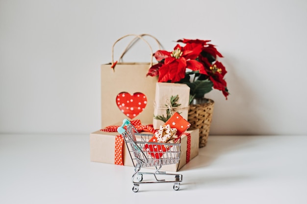 Christmas shopping and xmas sale season christmas mini shopping cart with red gift box poinsettias