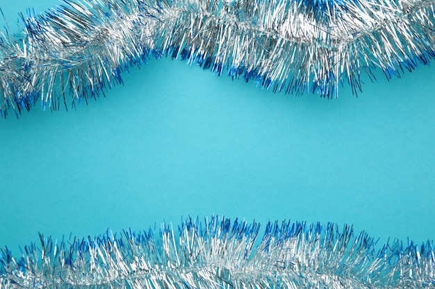 Christmas silver tinsel on blue background Space for text