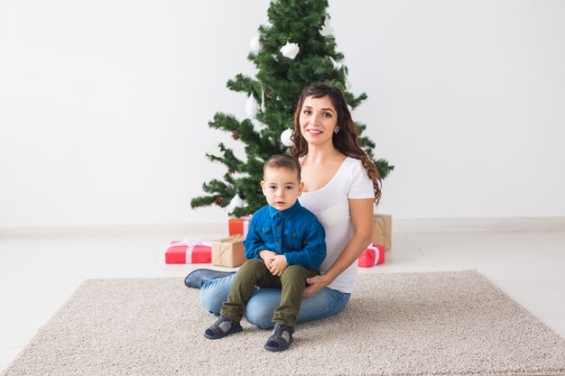 Christmas, single parent and holidays concept - Cute little boy holding christmas present for his mother at the home.