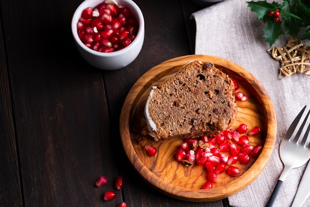 Christmas sliced chocolate cake with white icing and pomegranate kernels a wooden dark , flat lay