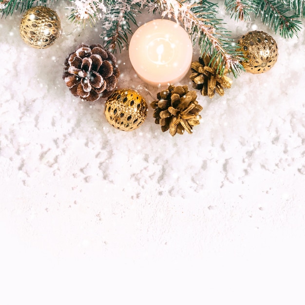 Christmas snow background. Burning candle, pine branches and cones