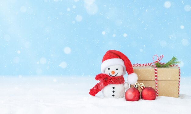Рождественский снежный фон с подарочной коробкой снеговика и рождественскими украшениями