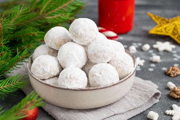 Christmas snowball cookies with walnuts and powdered sugar in a bowl with a cup of cocoa Copy space