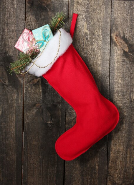 Фото Рождественский носок с подарками на деревянных фоне