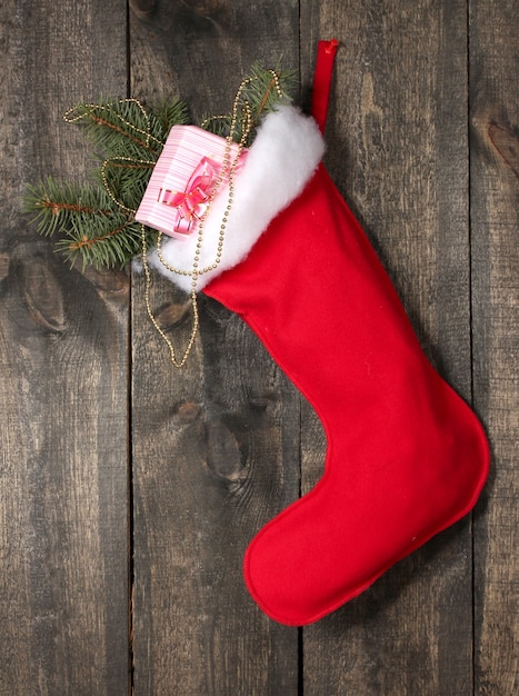 Christmas sock with gifts on wooden background