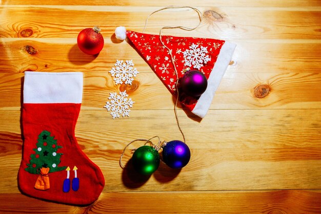 木の背景の上面図にボール雪片とクリスマスの靴下とサンタの帽子