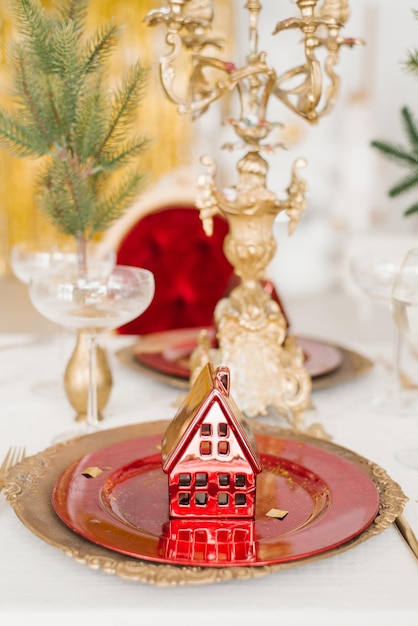 赤と金のプレートにクリスマスのお土産の赤い家 新年のお祝いディナーのサービングと装飾