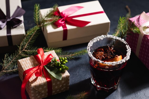 Рождественский дух и праздничный праздничный ассортимент подарков в подарочных коробках на черном фоне горячий и пряный глинтвейн в стакане
