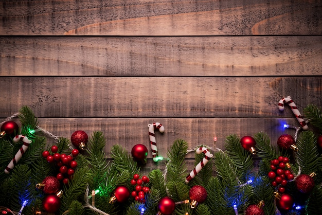 Christmas spruce branches, red ball, red berries on old wooden background.