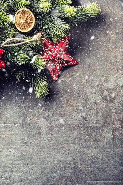 Christmas star spruce branches and cones on dark board.