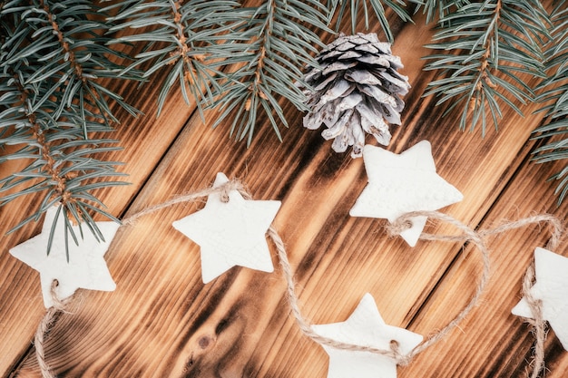 Christmas stars homemade cold porcelain garland with spruce branches on background of burnt wood, top view