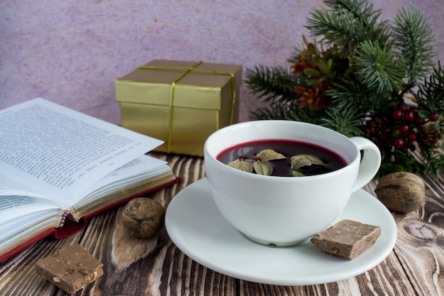 A christmas still life picture with a cup of hot wine book and
fir tree branches