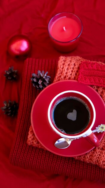 Christmas still life scene. Candle, pine cones, Christmas balls on knitted red background