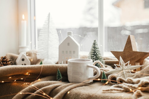 Christmas still life winter hygge home Warm cup of tea christmas decor and lights at window