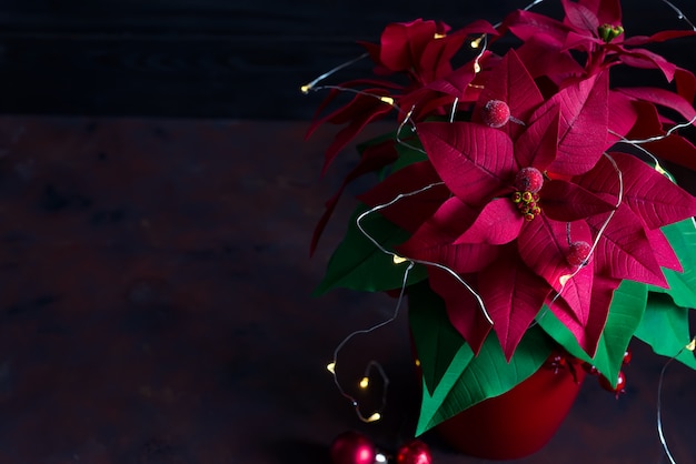 Christmas still life with poinsettia, gaultheria and decorations on wooden table