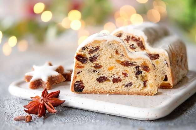 Christmas stollen on off white stone background with eucalyptus and garland xmas lights