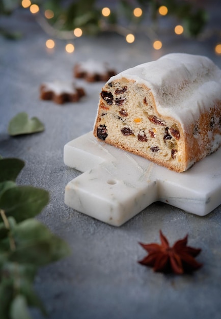 Christmas stollen on off white stone background with eucalyptus and garland xmas lights