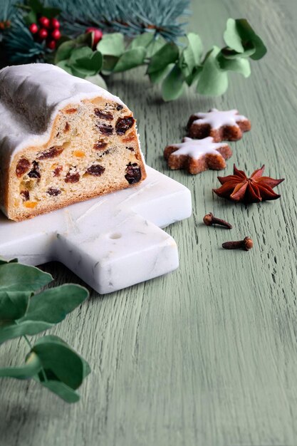 Christmas stollen on off white stone background with eucalyptus and garland xmas lights