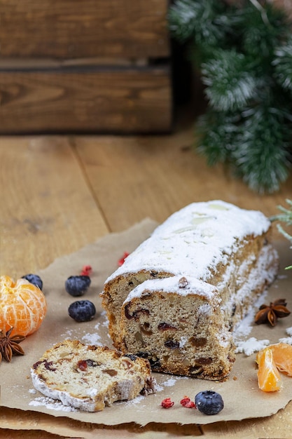 Christmas stollen with a mixture of dried fruits nuts and powdered sugar on a board