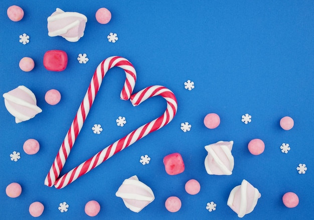 Foto dolci di natale su sfondo blu lecca-lecca e canne dolci caramello neve e capodanno vista dall'alto