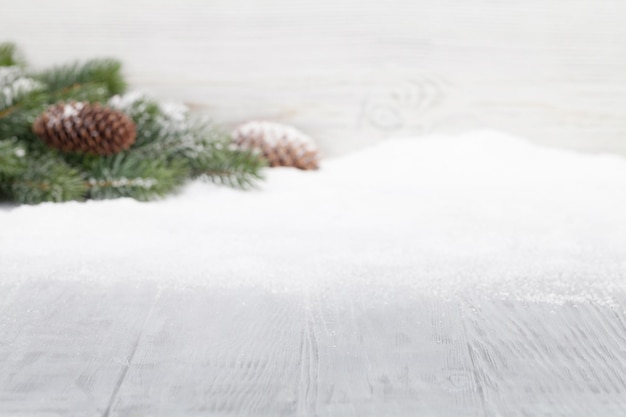 Photo christmas table backdrop with fir tree covered by snow out of focus in front of wooden wall xmas background with copy space