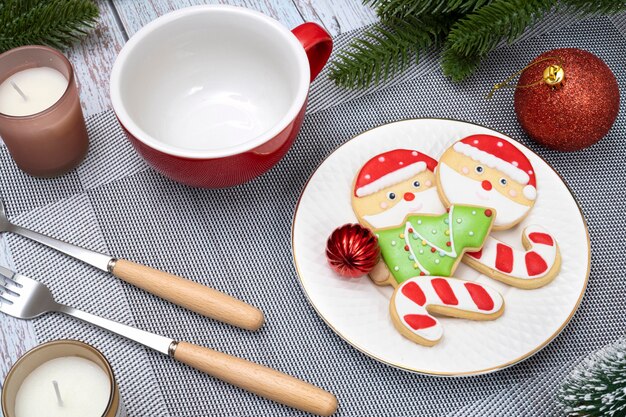 Christmas table decorations with red ceramic cup and a plate of sugar biscuits