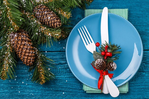 Christmas table place setting decorated sprig of mistletoe and christmas pine branches. New Year Clock Symbol. Christmas holidays background.