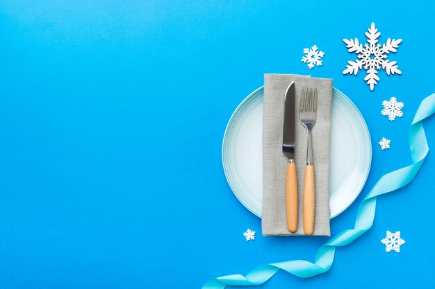 Christmas table place setting with christmas decor and plates, kine, fork and spoon. Christmas holiday background. Top view with copy space