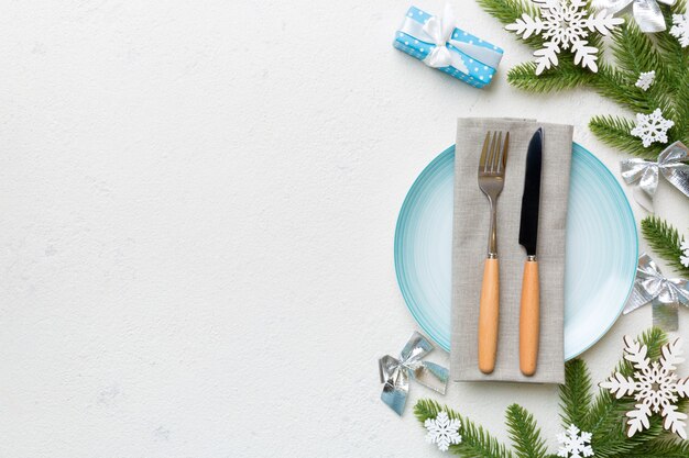 Christmas table place setting with christmas decor and plates, kine, fork and spoon. Christmas holiday background. Top view with copy space.