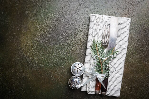 Christmas table place setting with christmas tree branches, knife and fork over dark table, top view with copyspace. Christmas holidays background