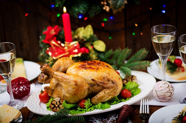 Christmas table served with a turkey, decorated with bright tinsel and candles