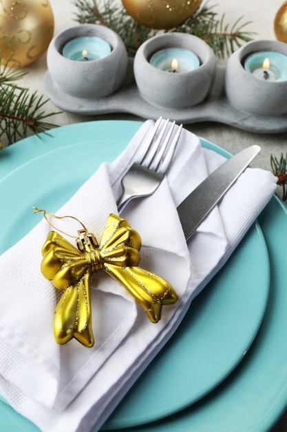 Christmas table setting in blue, golden and whitec olors on grey tablecloth surface