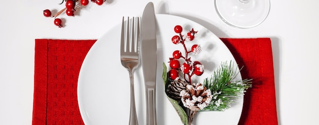 Christmas table setting Plate and cutlery on red napkin Decoration for festive dinner