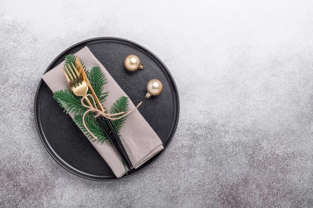 Christmas table setting with black ceramic plate, gifts and fir tree branch on stone background. Top view. Copy space - Image