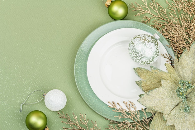 Christmas table setting with ceramic plates traditional decor on savannah green color background