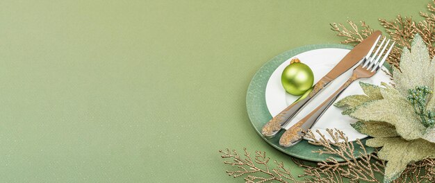 Сервировка рождественского стола с традиционным декором керамических тарелок на фоне зеленого цвета Саванны