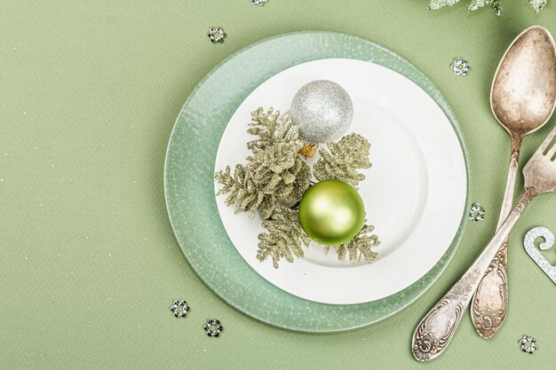 Christmas table setting with ceramic plates traditional decor on Savannah Green color background