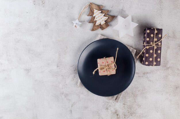 Christmas table setting with empty black plate and wooden decorations and dry oranges