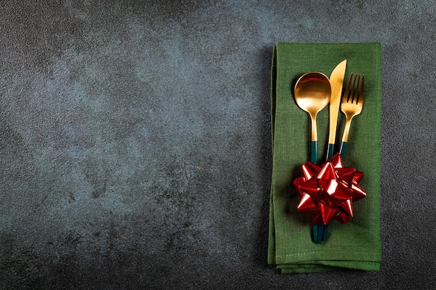 Christmas table setting with modern dishware and decorations on dark background. Top view. New Year place setting. Christmas tableware with decorations. Christmas place setting.