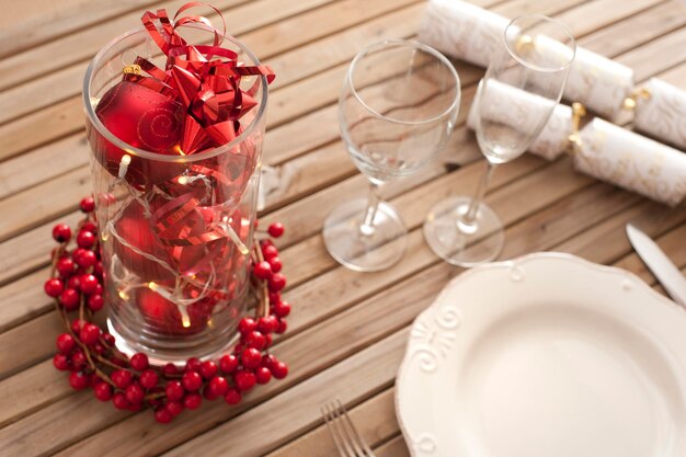 写真 祝う準備が整ったスラット付きの木製のテーブルに赤い装飾とベリーを飾ったクリスマステーブルのセット