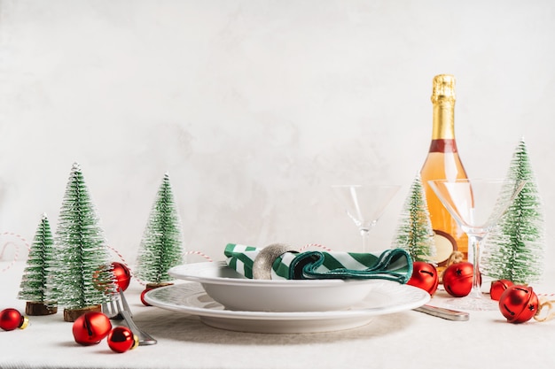 Christmas table setting with white plates, cutlery, napkin and with christmas decor on linen tablecloth with copy space. winter, festive concept table serving for new year.