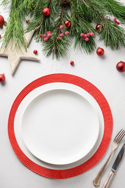 Christmas table setting with white and red elegant decorations on white table. View from above. Vertical format.