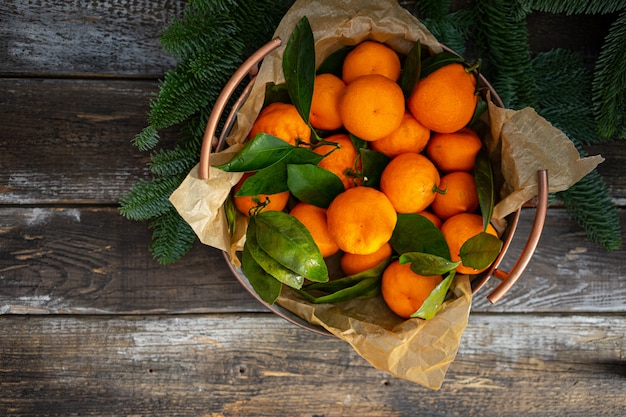 Photo christmas tangerine vintage copper bowl and fir branches. top view, horizontal