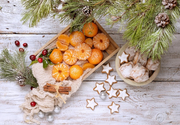 christmas tangerines and cupcakes on a wooden table. view from above