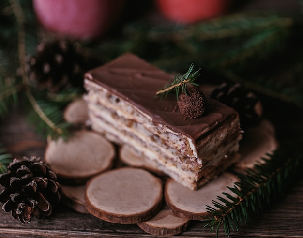 スプルースの装飾が施された暗い背景の木にクリスマスのおいしいケーキ。